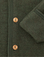 Close-up of a dark olive green wool jacket with a buttoned front and a folded cuff showing the ribbed lining.