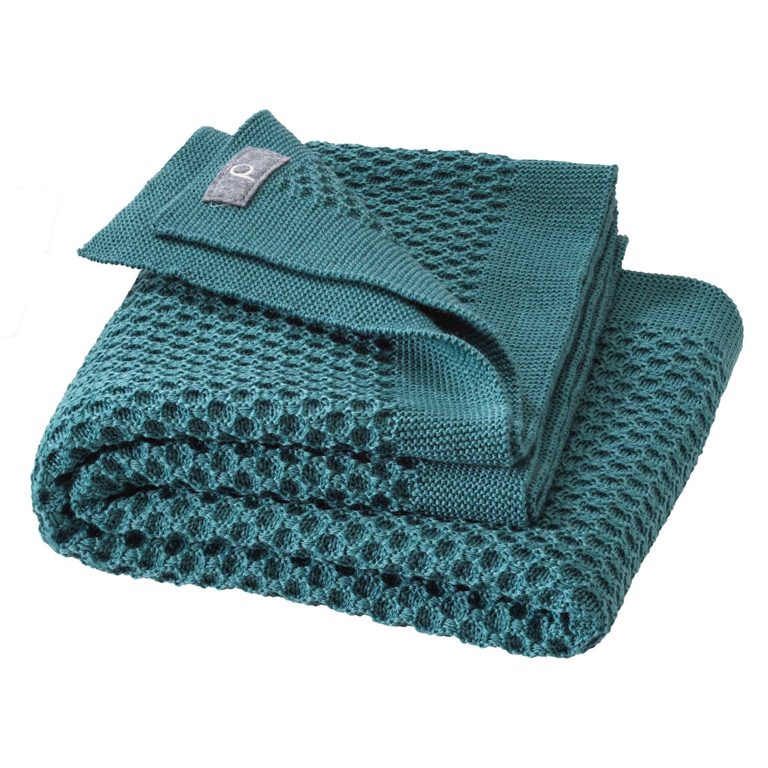 Teal knit blanket with a brand label on a white background