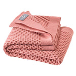 Folded pink textured blanket on a white background