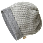 Grey knit beanie with a tag on a white background